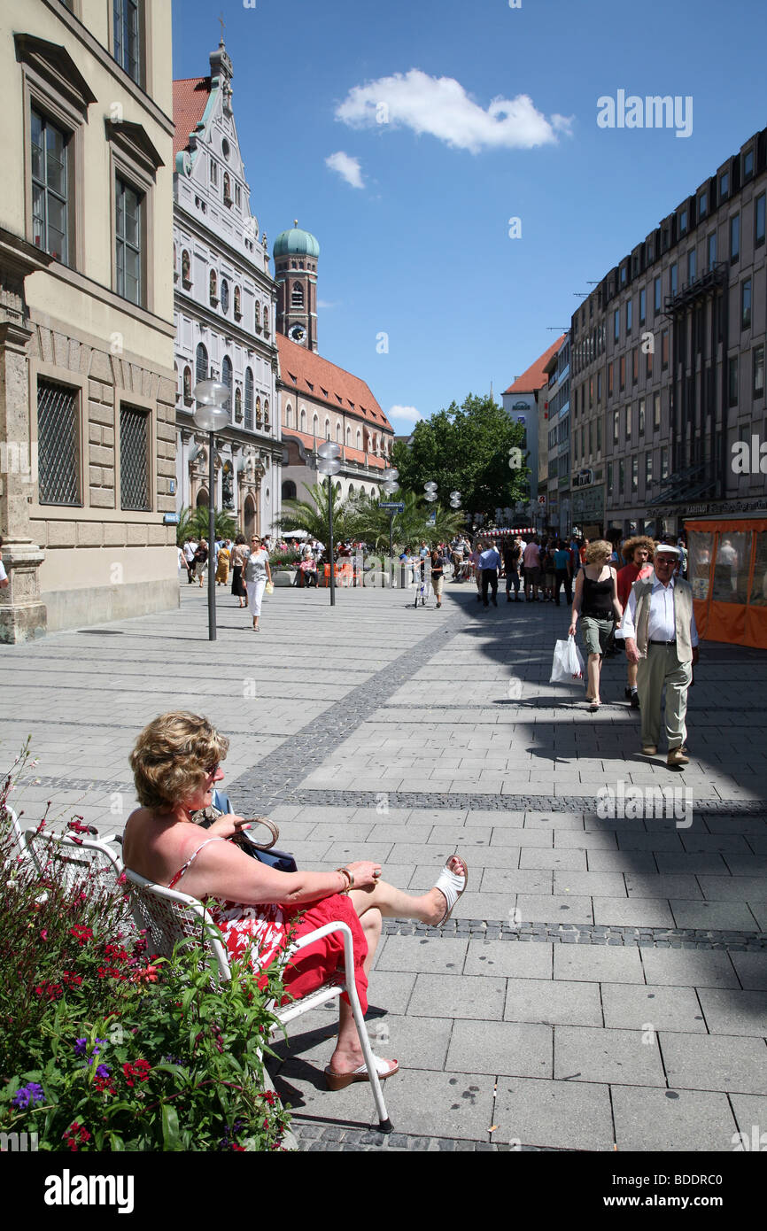 Frau sitzt in der Sonne auf die Kaufingerstrasse in München, Deutschland. Stockfoto