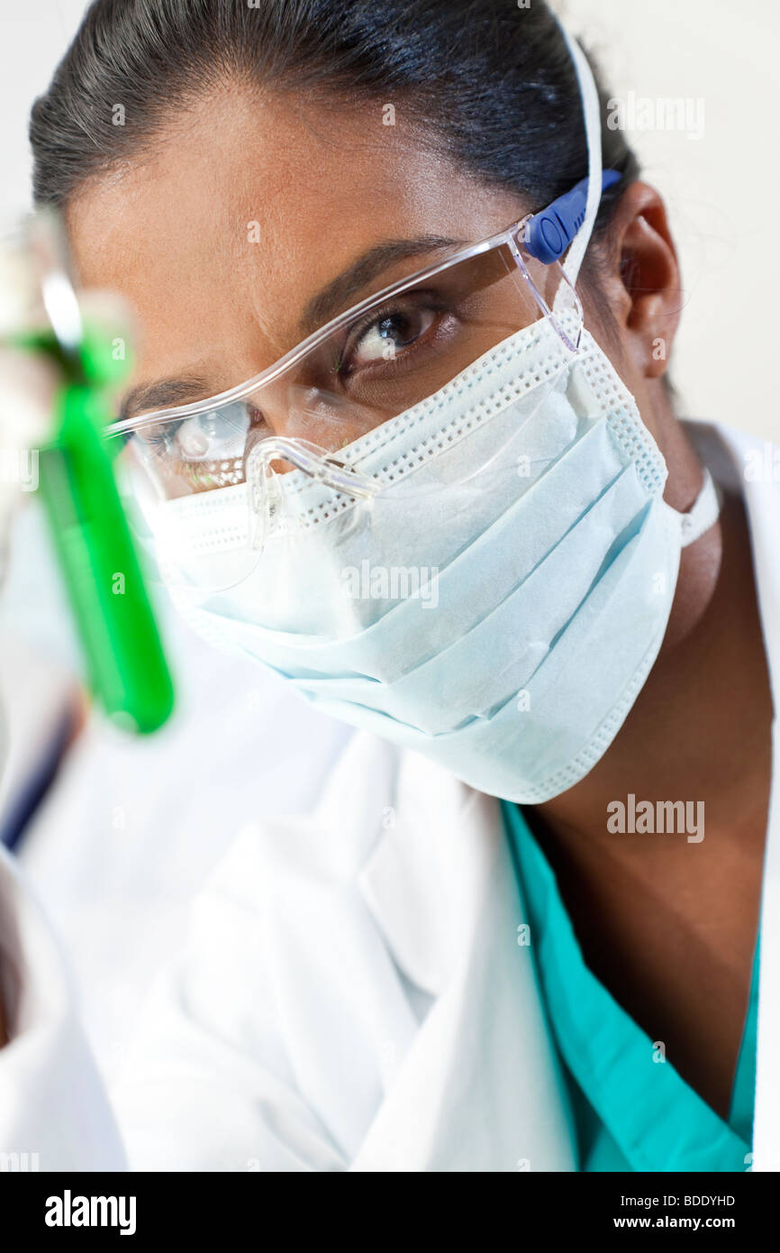 Eine asiatische medizinische oder wissenschaftliche Forscher oder Arzt ein Reagenzglas grüne Lösung in einem Labor zu betrachten. Stockfoto