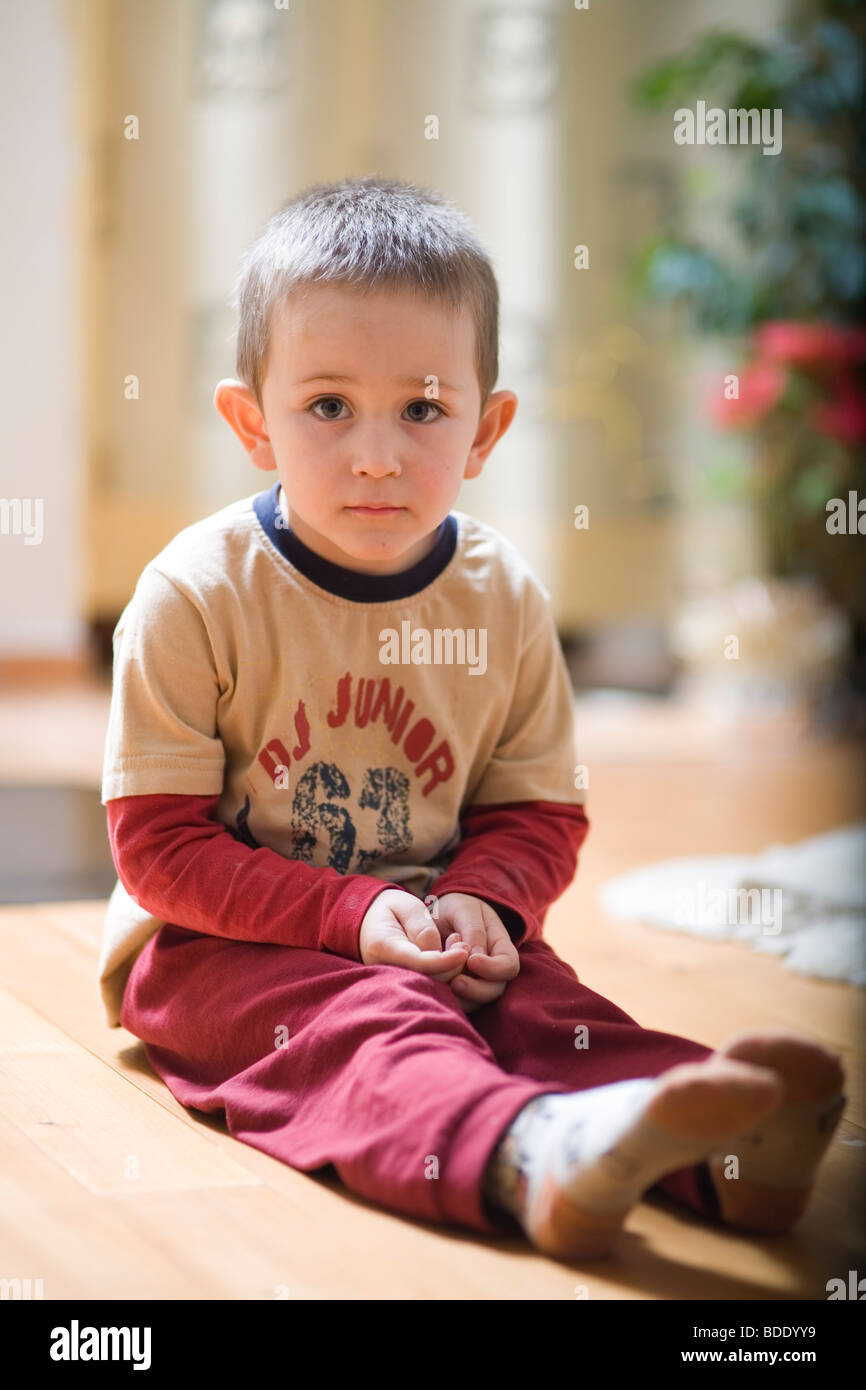 Porträt eines kleinen Jungen auf dem Boden sitzend Stockfoto