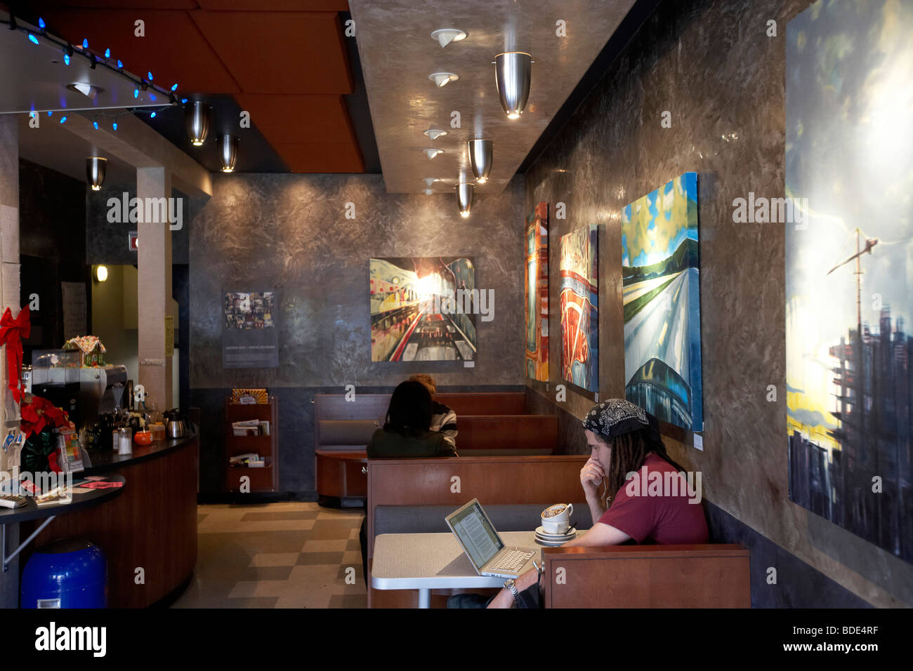 Mann mit drahtlosen Internet-Laptop-Computer im Café Diner.  Kunst auf Wänden. Stockfoto