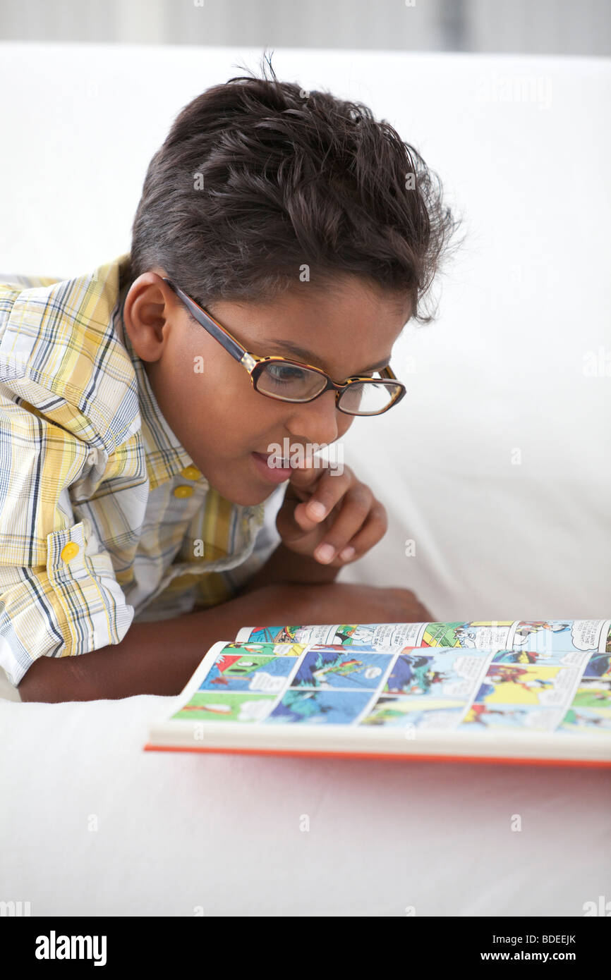 Kleiner Junge ist ein Streifen-Buch lesen. Stockfoto