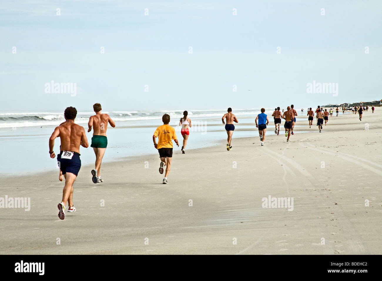 Läufer laufen unten am Strand in einem Rennen durch den Ozean auf dem Sand in Jacksonville Beach, Florida Stockfoto