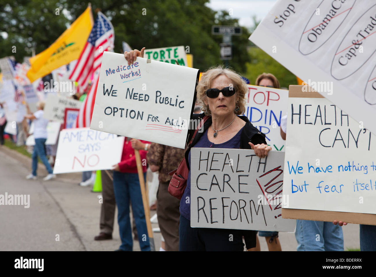 Ein Befürworter der Reform des Gesundheitswesens hält ihr Zeichen umgeben von Menschen gegen Reformvorschläge Stockfoto