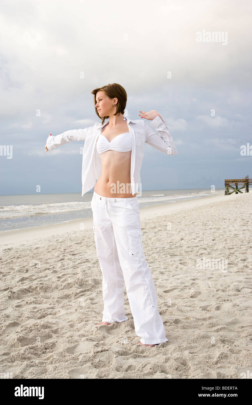 Junge Frau im weißen Bikini-Oberteil und Hose stehen auf dem Strand  ausdehnen Stockfotografie - Alamy