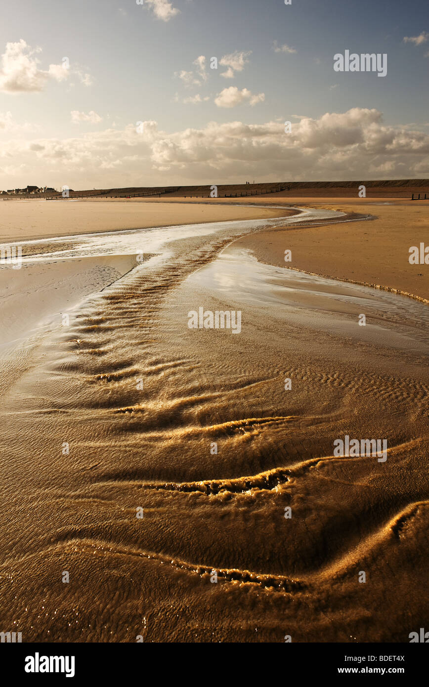 Ein Wasserbach fließt am Strand von Camber Sands in East Sussex. Stockfoto