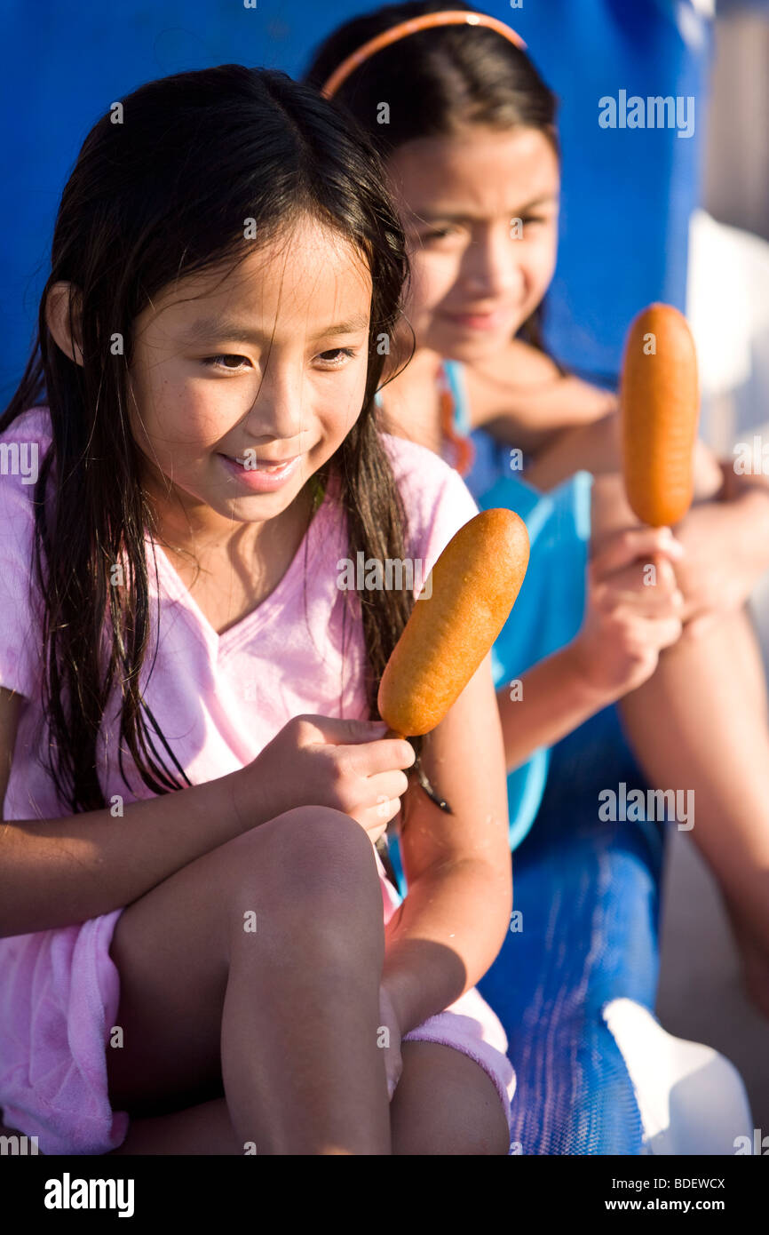 Junges Mädchen essen Corndog im Wasserpark im Sommer Stockfoto