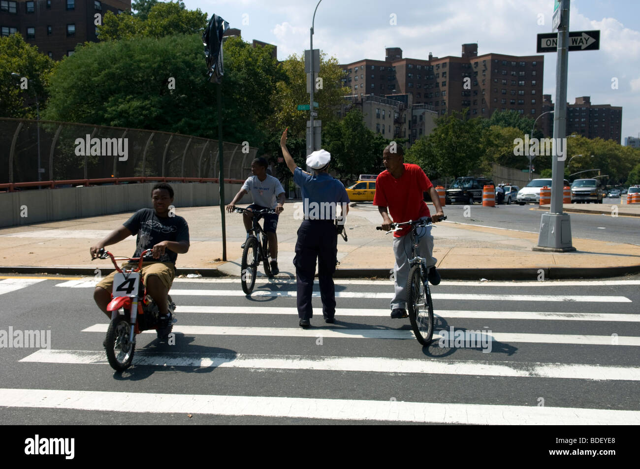 Unter der Regie von einem NYPD überqueren Traffic Officer Kinder auf dem Fahrrad Houston Street auf den FDR Drive in New York Stockfoto