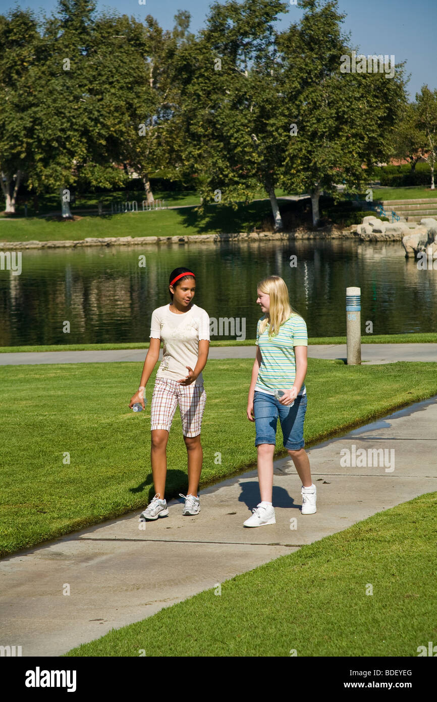 Zwei Rassen gemischt rassisch gemischten Mädchen hängen zusammen hängen. Hispanic und kaukasischen Junior high Mädchen zu Fuß Bürgersteig in den Park gehen. Herr © Myrleen Pearson Stockfoto