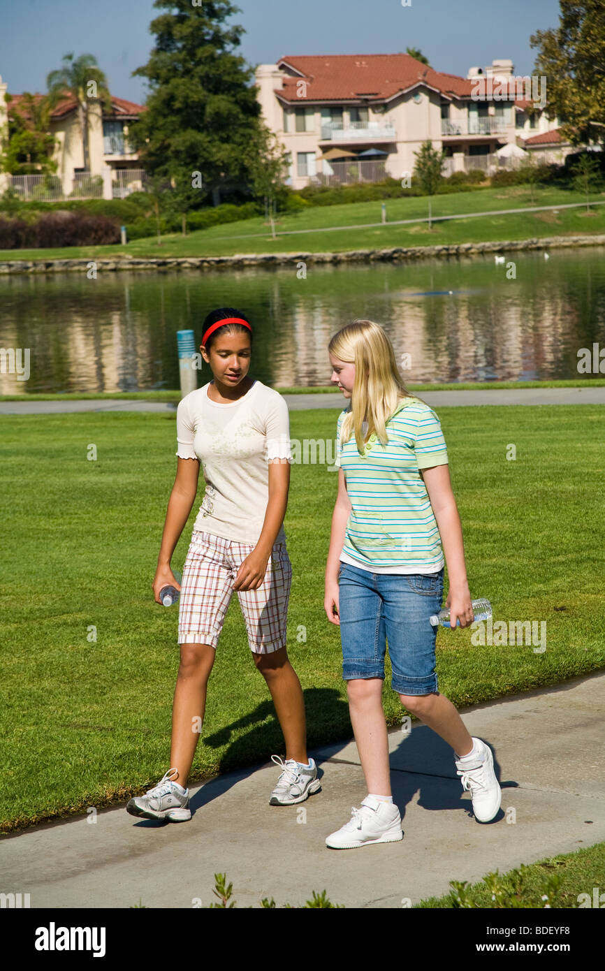Tween-Tweens Hispanic und kaukasische Mädchen im Teenageralter gehen und sprechen im Park abhängen. Herr © Myrleen Pearson Stockfoto