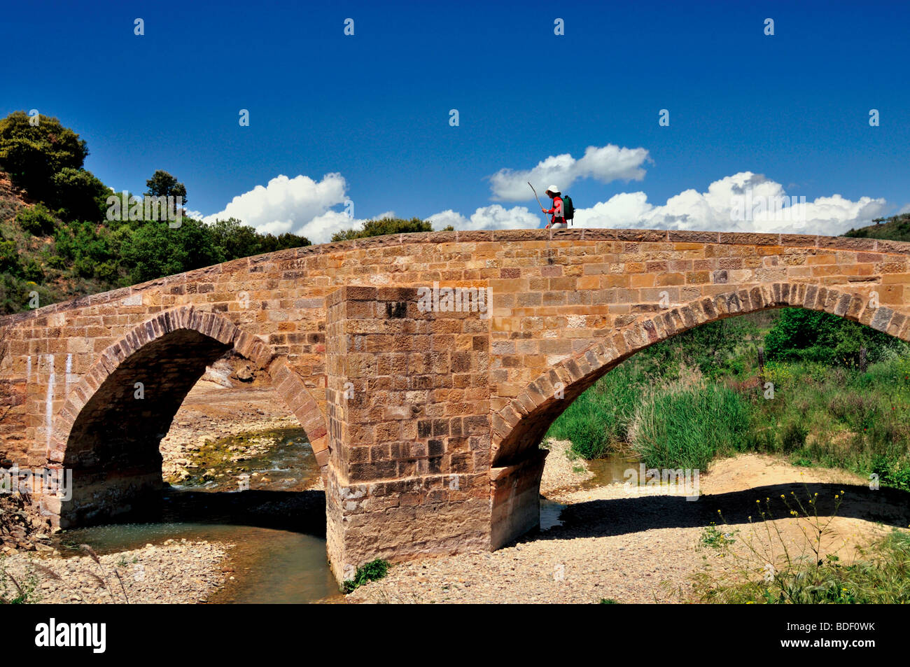 Spanien, Jakobsweg: Pilger vorbei an mittelalterlichen Brücke über Fluss Salado zwischen Estella und Cirauqui Stockfoto