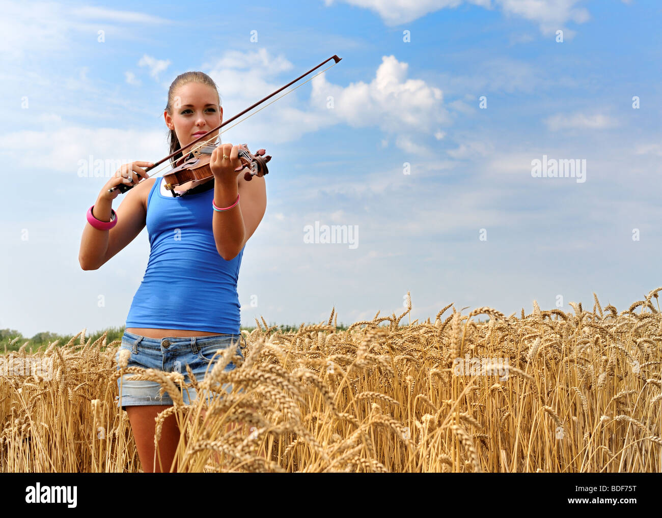 junge attraktive Frau mit dem Geigenspiel im Land Stockfoto