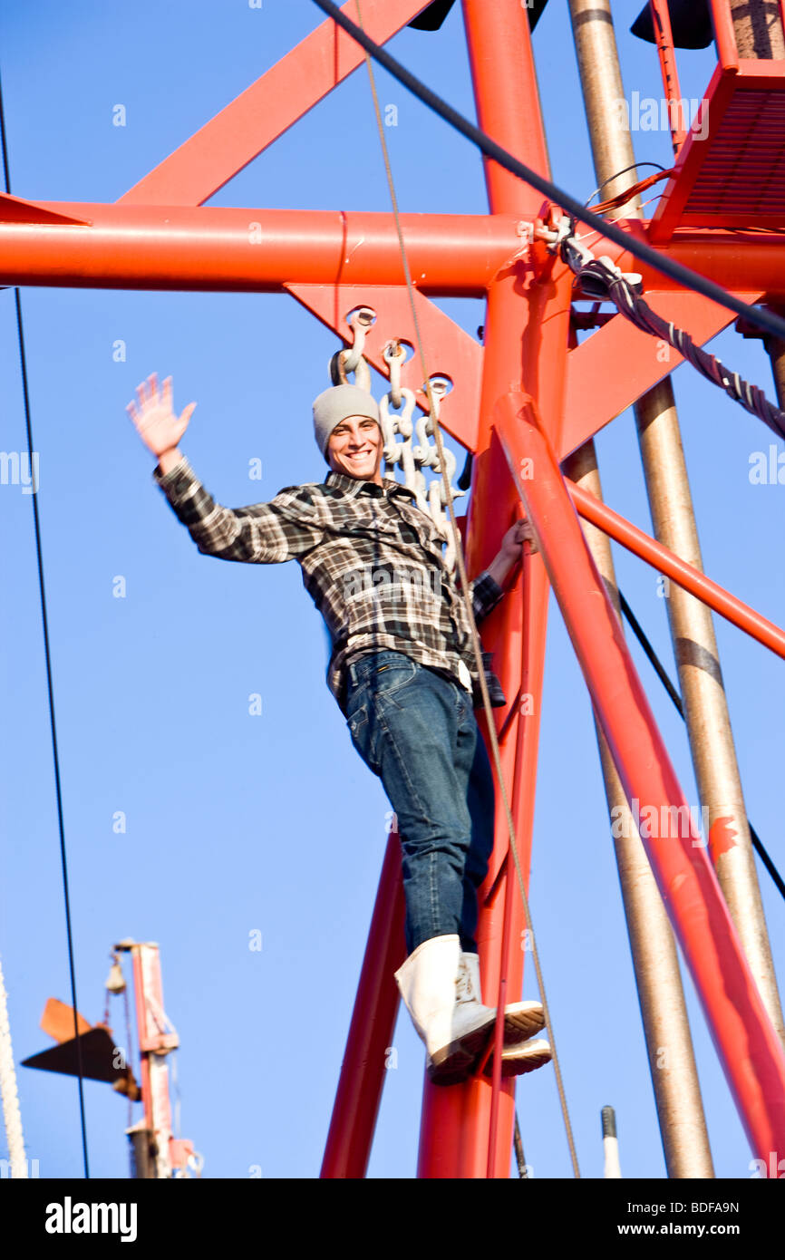 Junge Fischer im karierten Hemd Klettern auf Fischerboot und winken Stockfoto