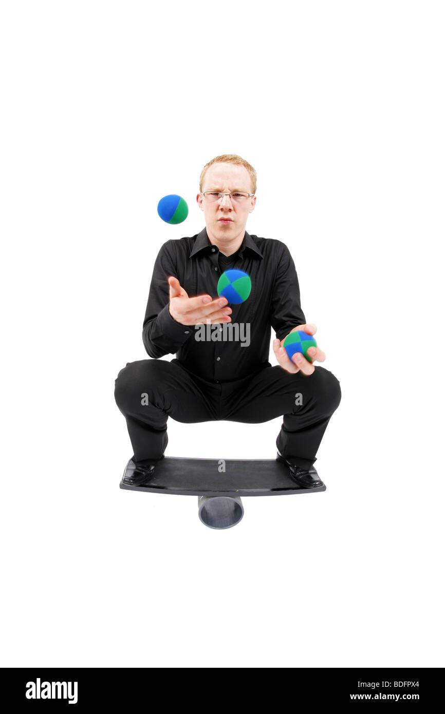 junger Mann mit Bällen jonglieren und balancieren auf einem Rola Bola-Balance-board Stockfoto