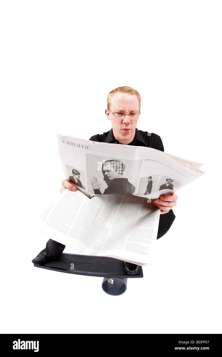 junger Mann an Bord Zeitung lesen und balancieren auf roll Stockfoto