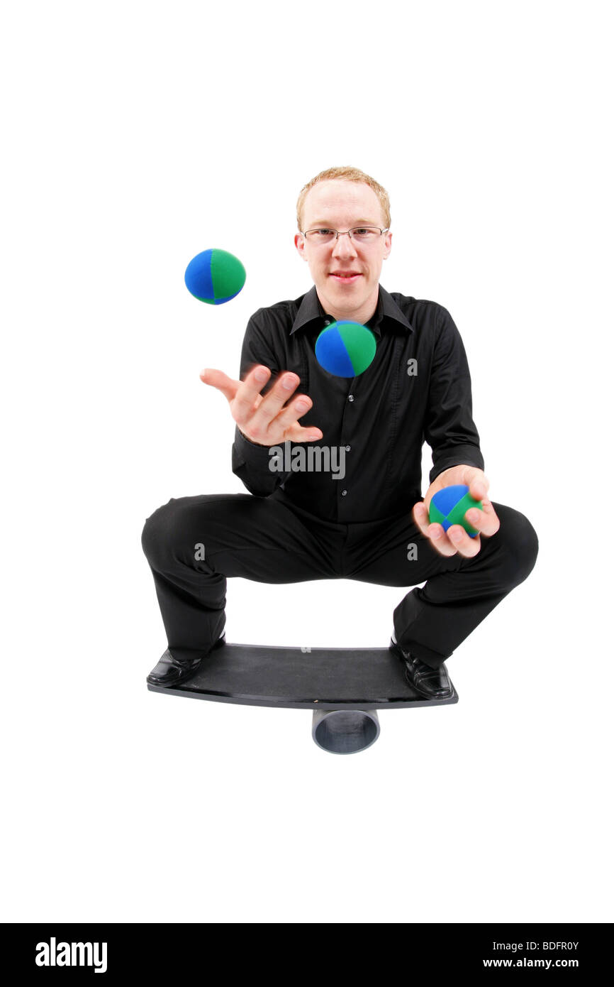 junger Mann mit Bällen jonglieren und balancieren auf einem Rola Bola-Balance-board Stockfoto