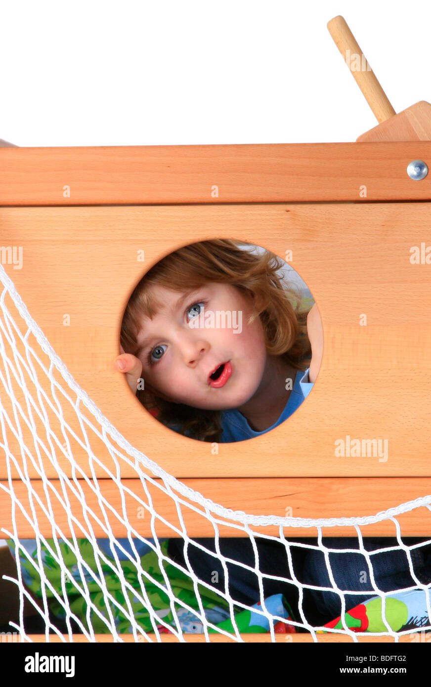 kleiner Junge spielt in einem Blick durch ein Loch Billi-Bolli-Hochbett Stockfoto