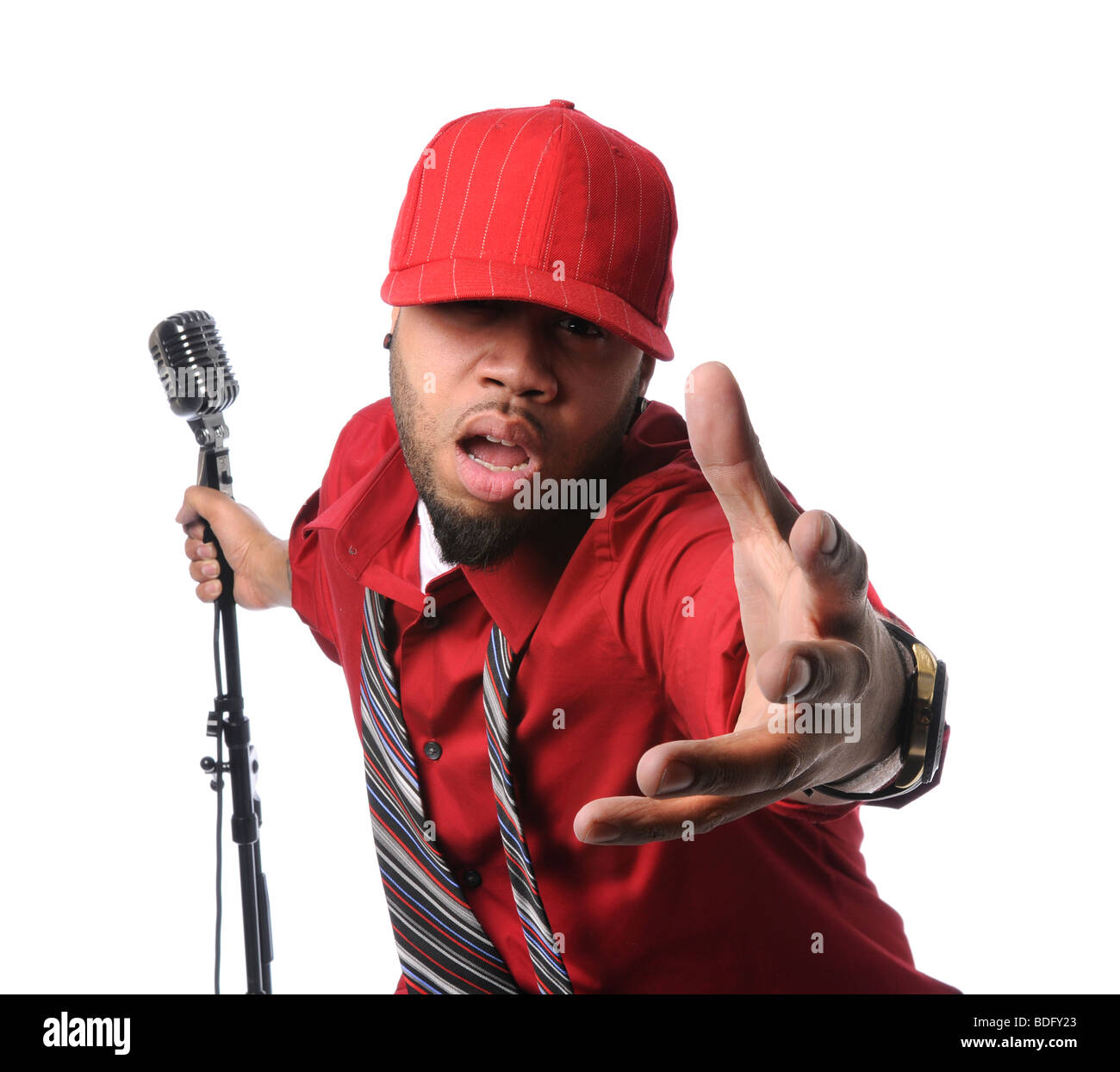Afrikanische amerikanischer Mann gekleidet in roten Shirt und Cap singen und halten Vintage Mikrofon Stockfoto