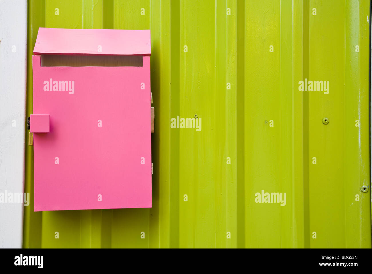 Hell rosa Briefkasten gegen eine grüne Wand Stockfoto