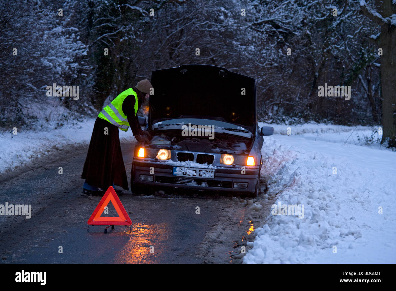 Frauen auf eigene Faust aufgeschlüsselt im Schnee mit Warndreieck, gestrandeten versuchen um es fest mit fluoreszierenden Jacke Stockfoto