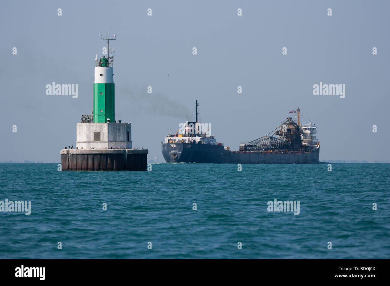 Ein Leuchtturm und ein See-Frachter in Lake St. Clair, Michigan. Stockfoto