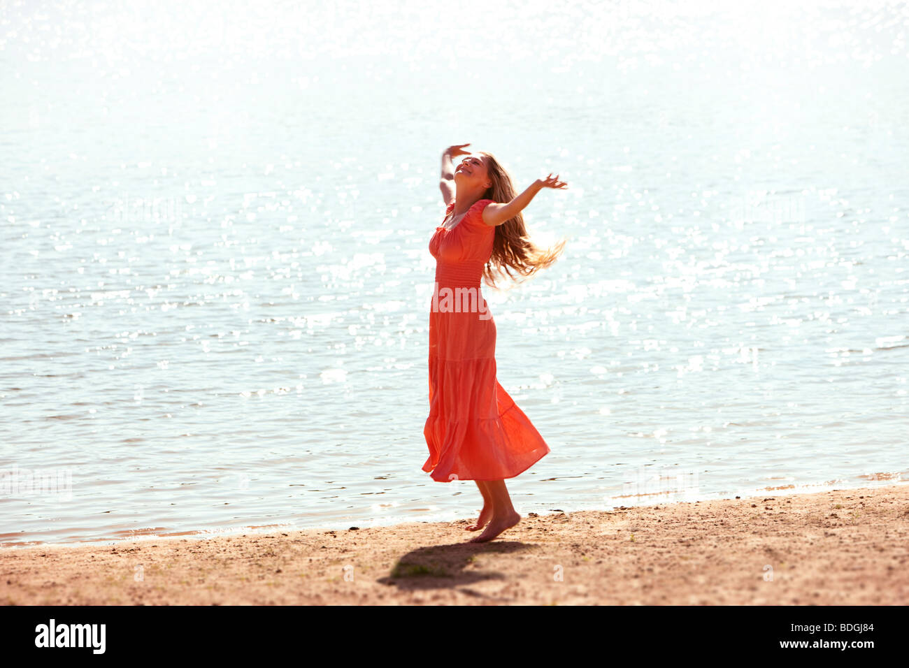 Frau tanzt am Strand mit Hingabe, Arme ausgestreckt. Stockfoto