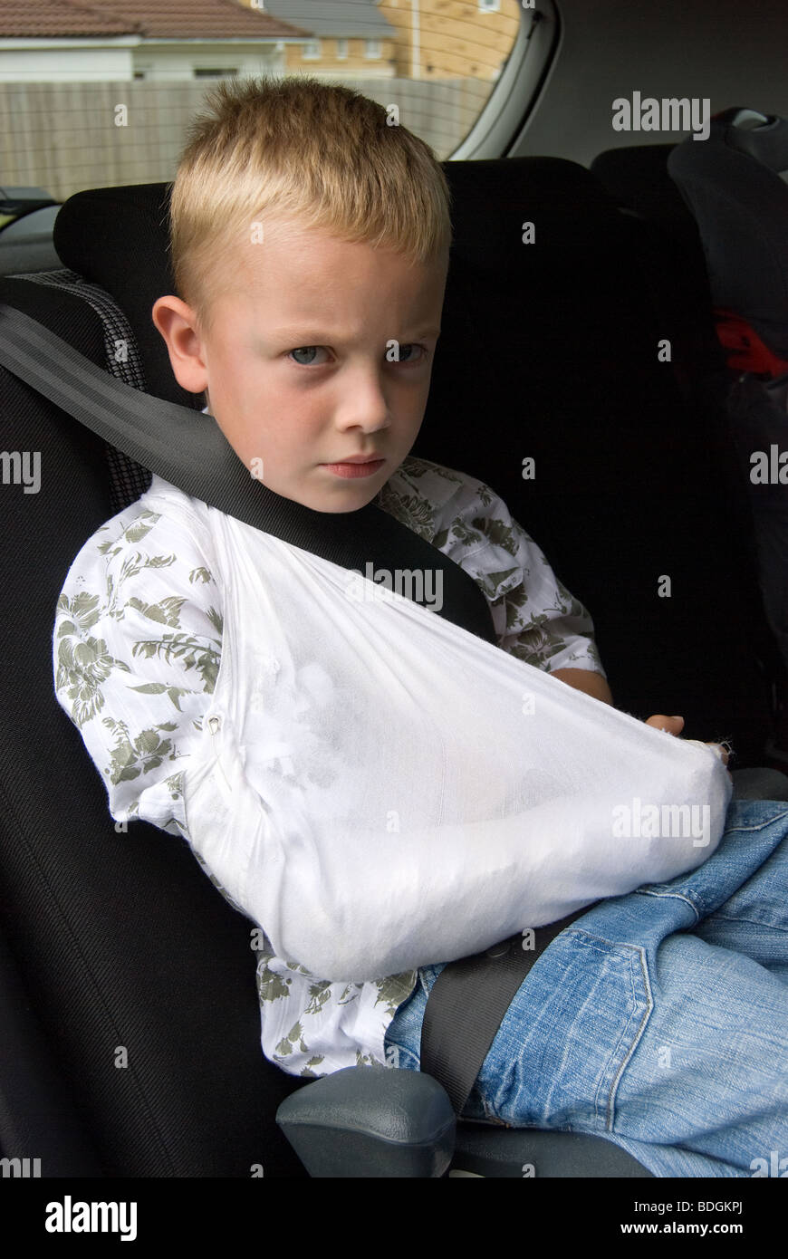 Junge sitzt in einem Auto mit einem gebrochenen arm Stockfoto