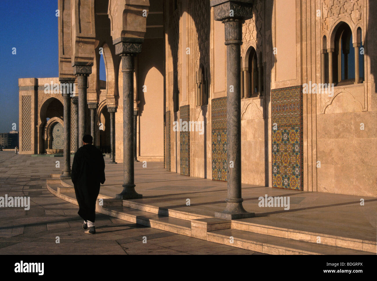 Mann mit traditioneller Kleidung zu Fuß entlang der Moschee bei Sonnenuntergang in Casablanca - Marokko Stockfoto