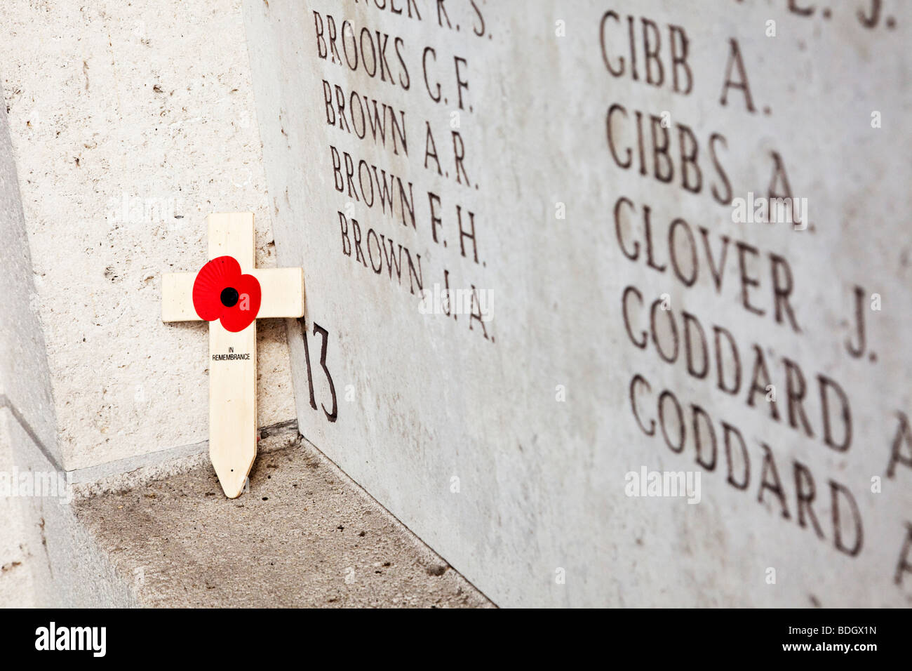 Einsamer Mohn Kreuz links an der Wand mit Namen von vermissten Soldaten in der Gedenkstätte Menin Gate WW1 bei Ypern, Belgien Stockfoto