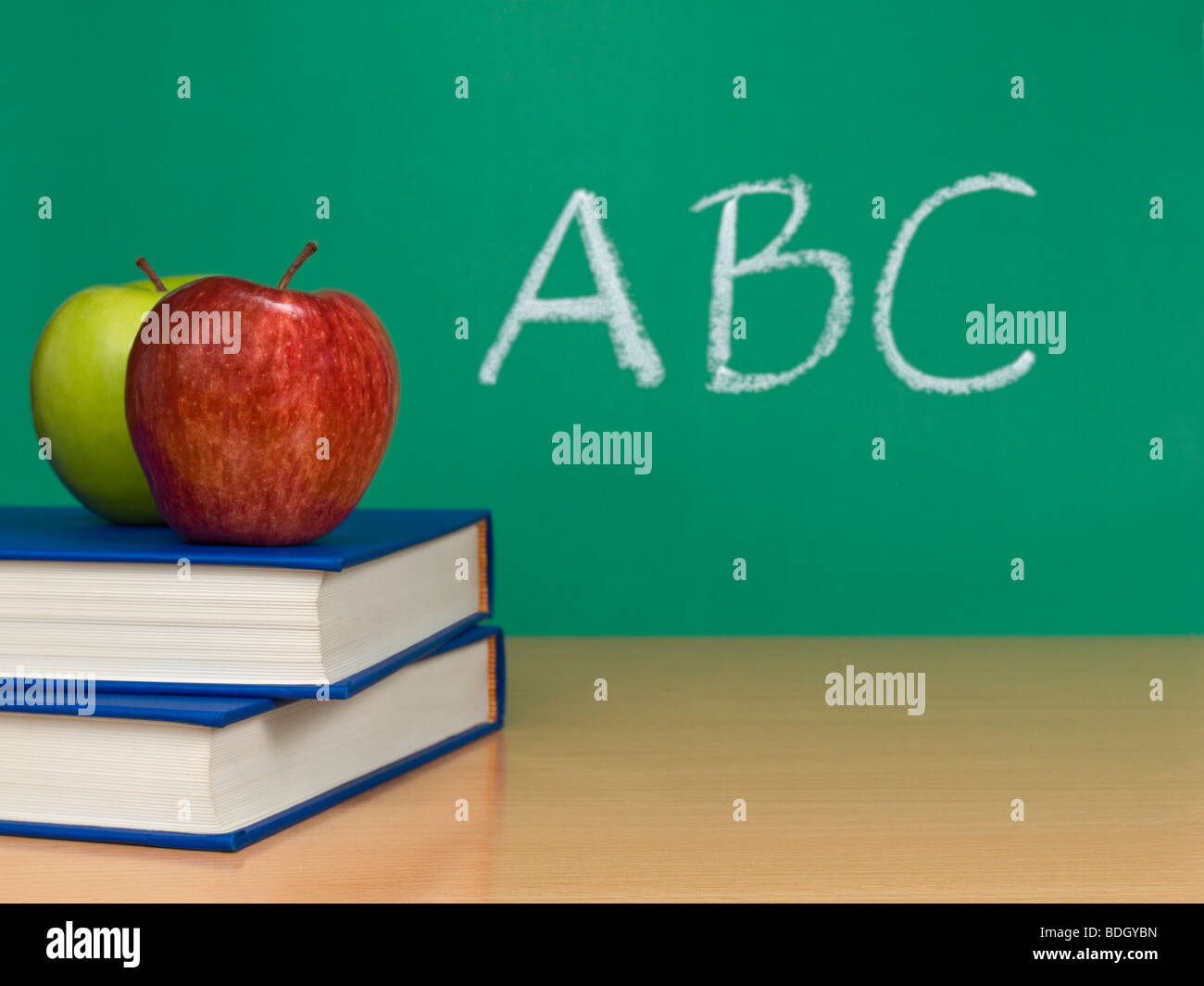 ABC auf einer Tafel geschrieben. Zwei Äpfel über Bücher im Vordergrund. Stockfoto