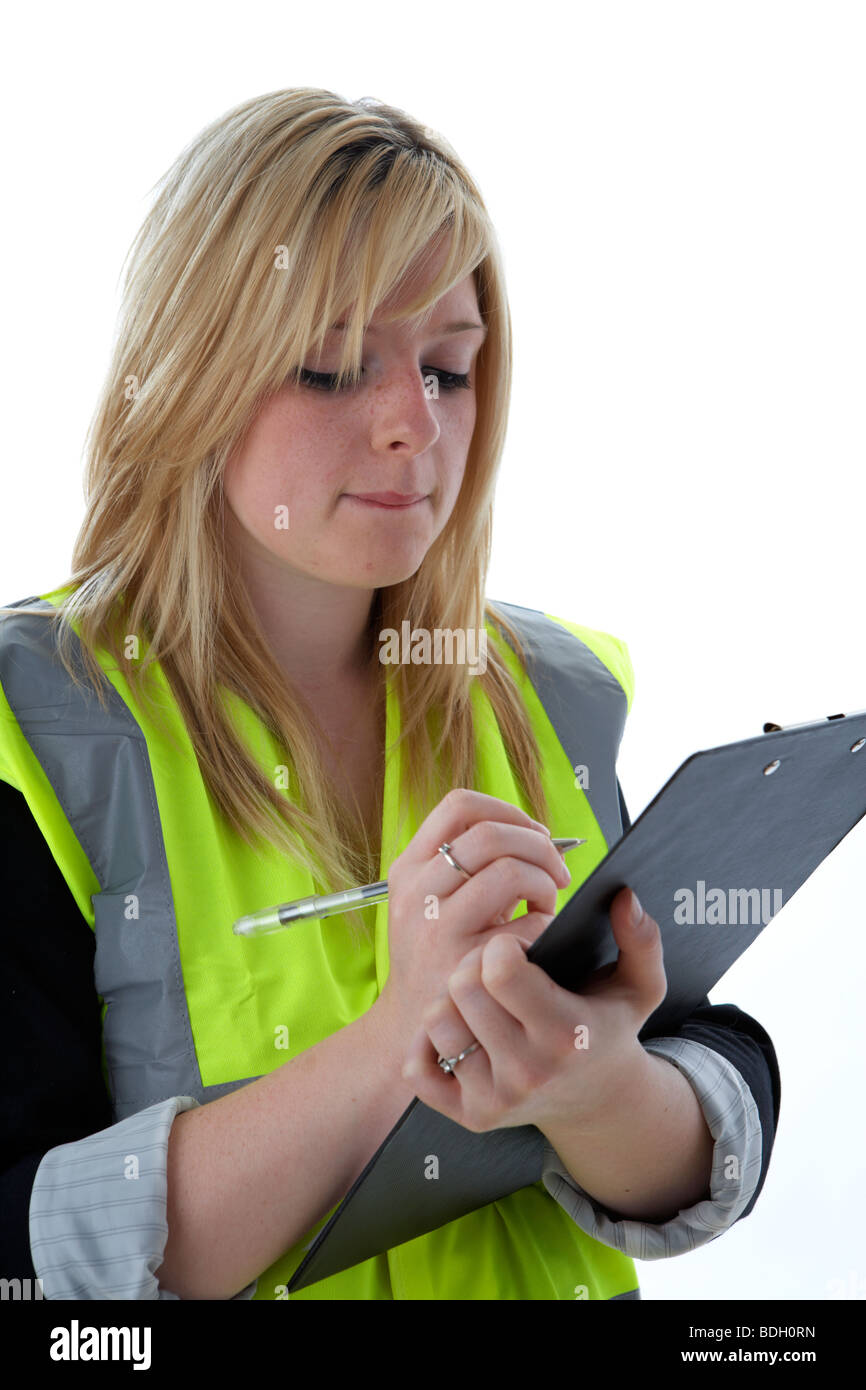 junge 20 jährige blonde Frau trägt hohe Vis Weste Lesung Notizen, die sie auf einem Klemmbrett übernommen hat Stockfoto