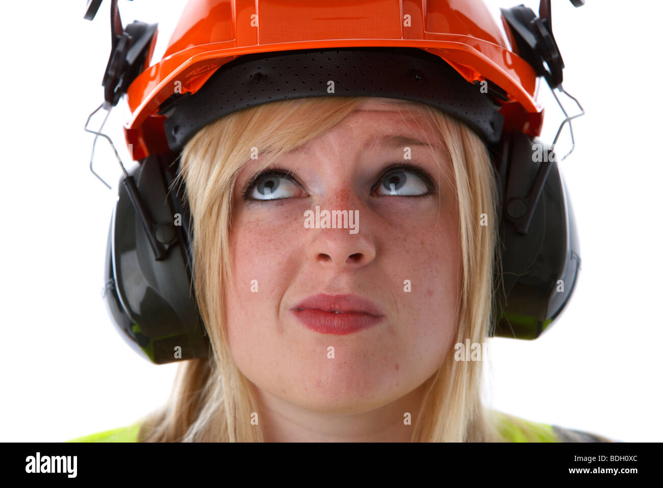 junge 20 jährige blonde Frau blickte verwirrt tragen orange Schutzhelm Ohr Protektoren Visier und hohe Vis Weste Stockfoto