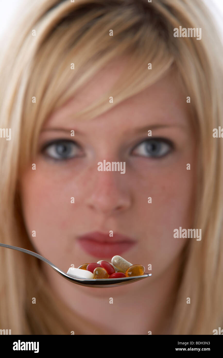 junge 20 jährige blonde Frau mit einem Löffel Vitamin Ergänzungen Stockfoto