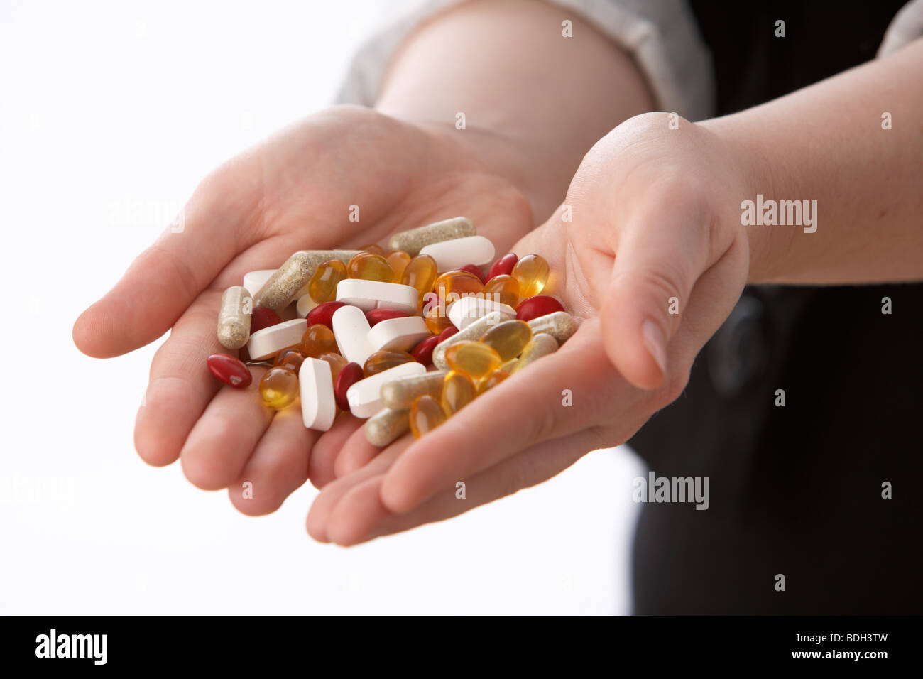 junge 20 jährige Frau mit einer Handvoll verschiedener Vitamin-Ergänzungen Stockfoto