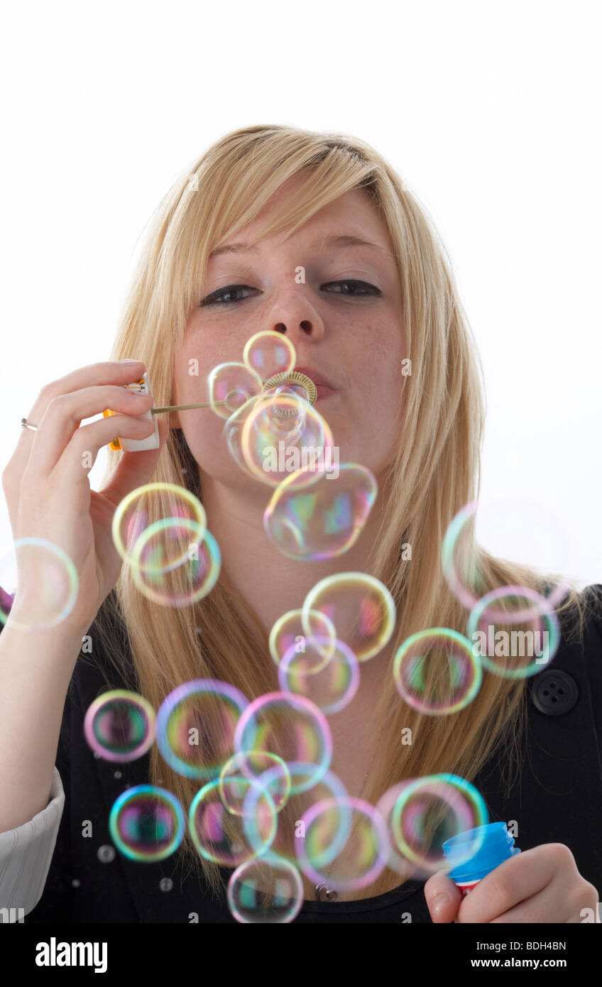 junge 20 jährige blonde Frau bläst Seifenblasen aus einem Kinder-Spielzeug Stockfoto