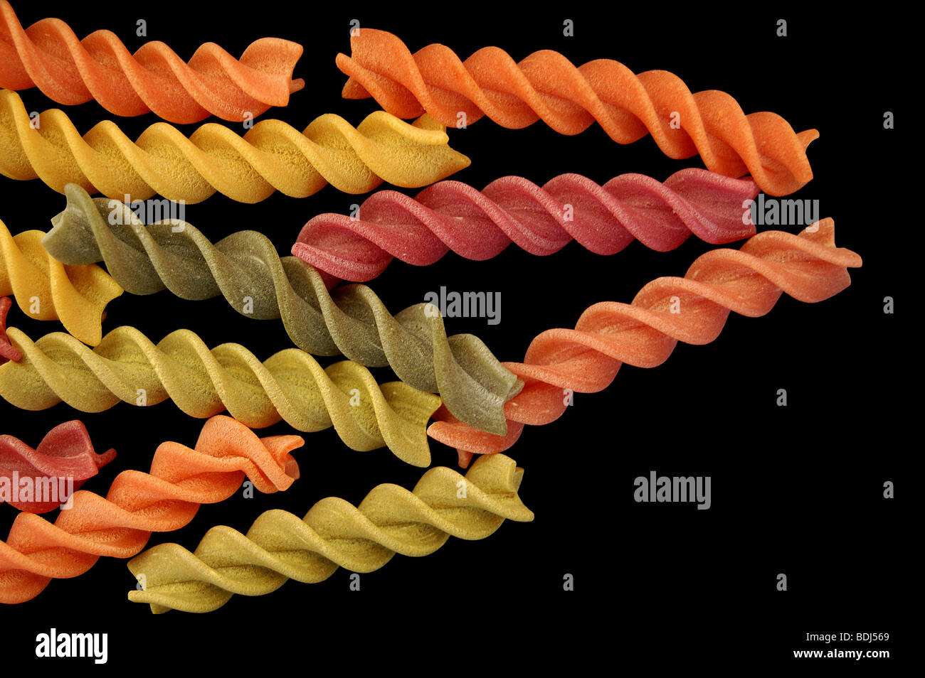 Multi farbige Fusilli wirbelt Nudeln vor einem schwarzen Hintergrund. Stockfoto