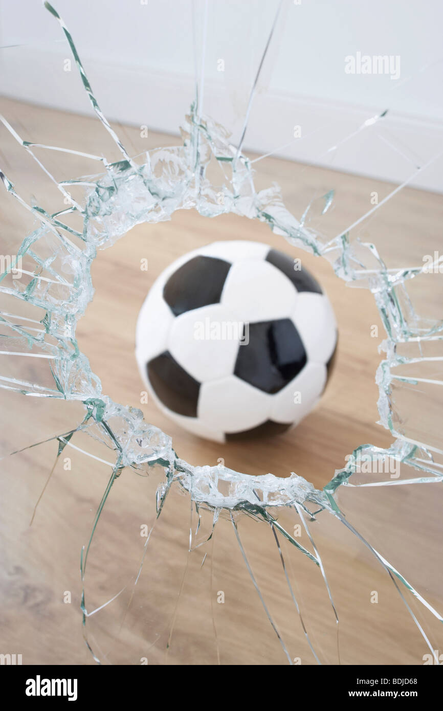 Fußball und zerbrochenes Fenster Stockfoto