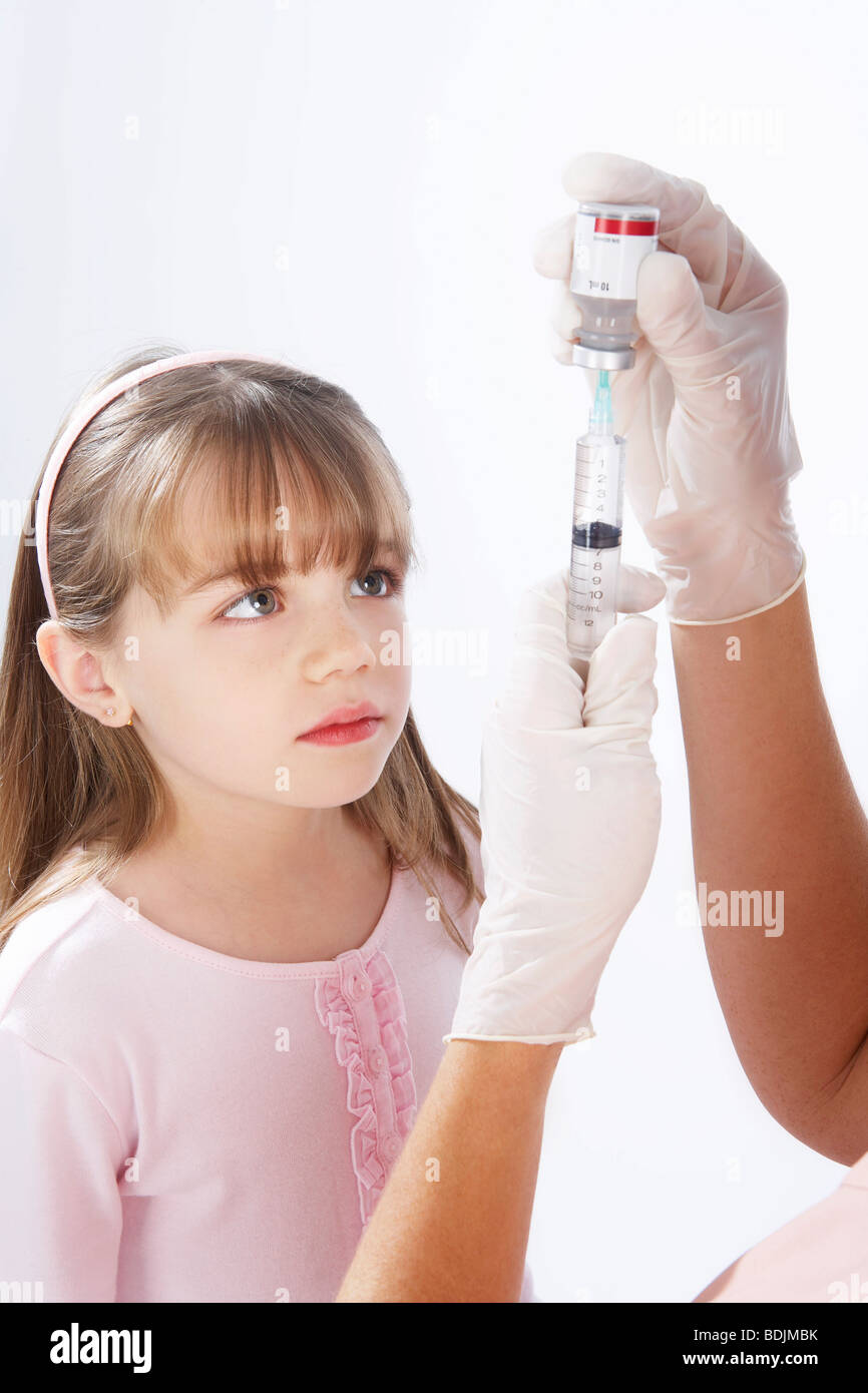 Kleine Mädchen beobachten Krankenschwester eine Nadel vorbereiten Stockfoto
