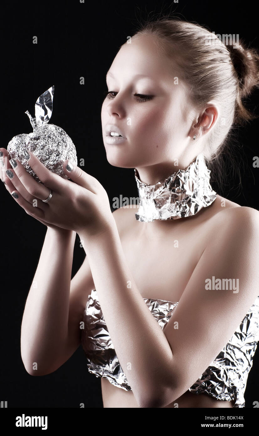Roboter-Frau mit metallischen Apfel. Auf dunklem Hintergrund. Stockfoto