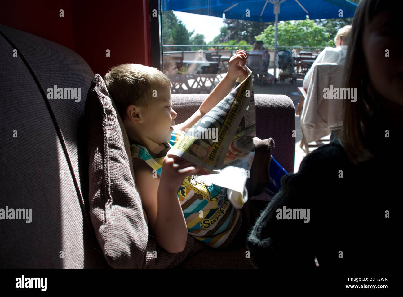 Kleiner Junge liest eine Boulevardzeitung Stockfoto