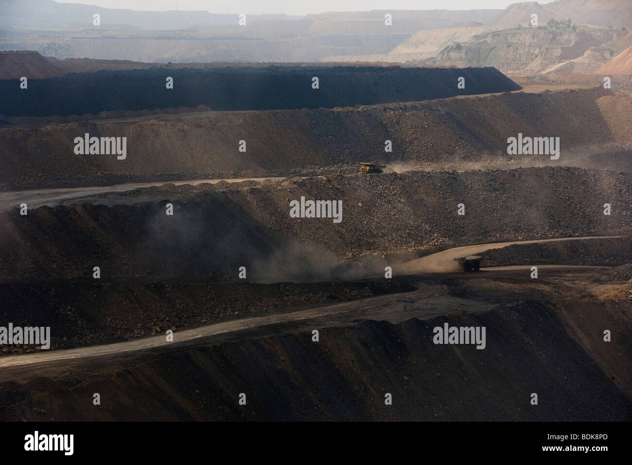 EIN TAI BAO MINE, Provinz SHANXI, CHINA - AUGUST 2007: LKW werfen Staub wie sie Kohle aus dieser riesigen Tagebau-Mine sammeln Stockfoto