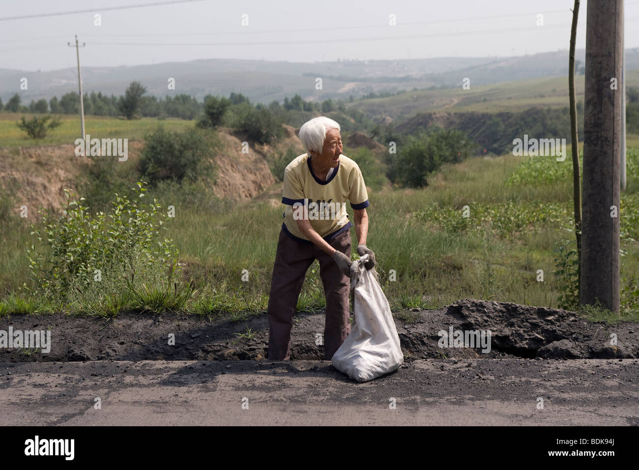 DATONG, Provinz SHANXI, CHINA - AUGUST 2007: Eine arme Frau sammelt Kohle sank vorbei LKW Kohle als Brennstoff zu verwenden. Stockfoto