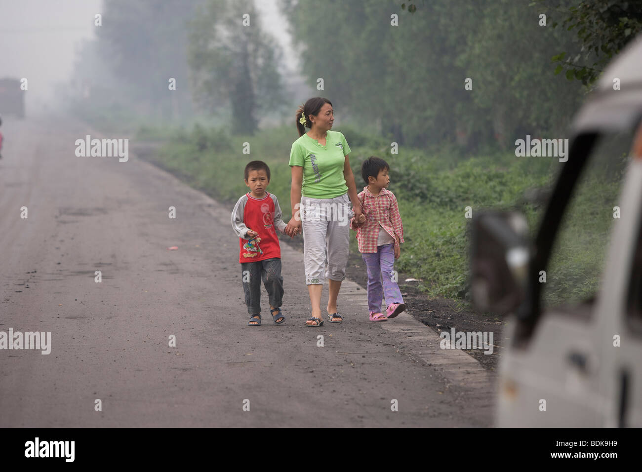 QING XU, TAIYUAN, Provinz SHANXI, CHINA - August 2007: Eine Mutter mit ihren Kindern in der Nähe von Kokereien Fabriken geht. Stockfoto