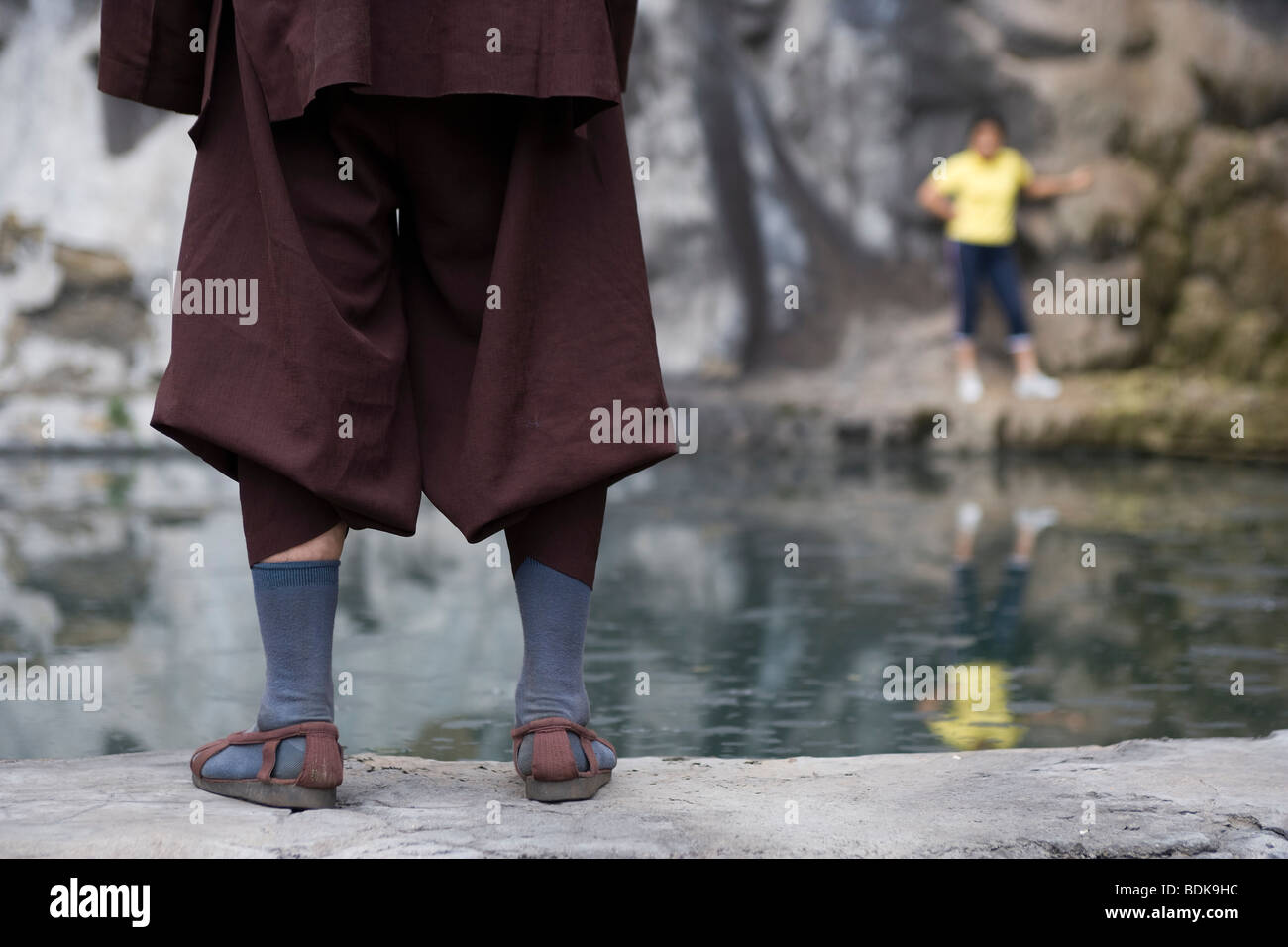 JIEXIU, Provinz SHANXI, CHINA - AUGUST 2007: Ein Mönch steht am Rande eines Teiches Tempel in seiner Sandalen im Gespräch mit einem Besucher. Stockfoto