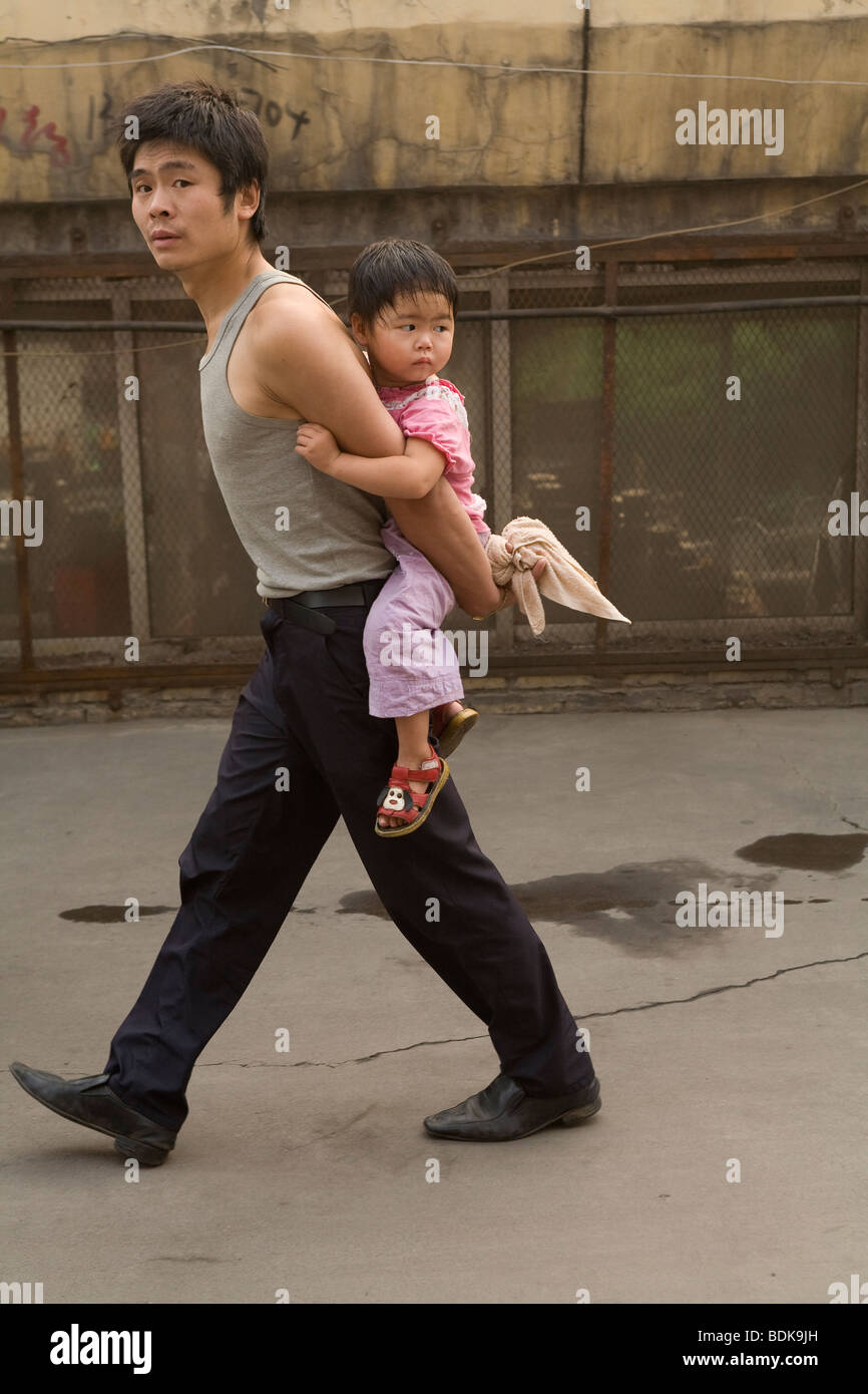 JIEXIU, Provinz SHANXI, CHINA - AUGUST 2007: Ein junger Vater seine Tochter auf dem Rücken trägt bei He Blätter des Bahnhofs. Stockfoto