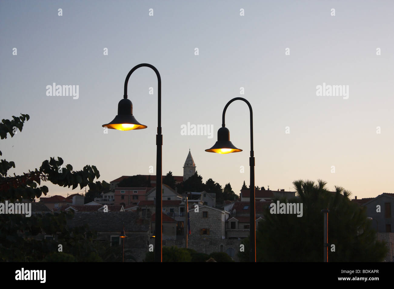 Zwei Straßenlaternen mit einer mediterranen Stadt im Hintergrund. Stockfoto