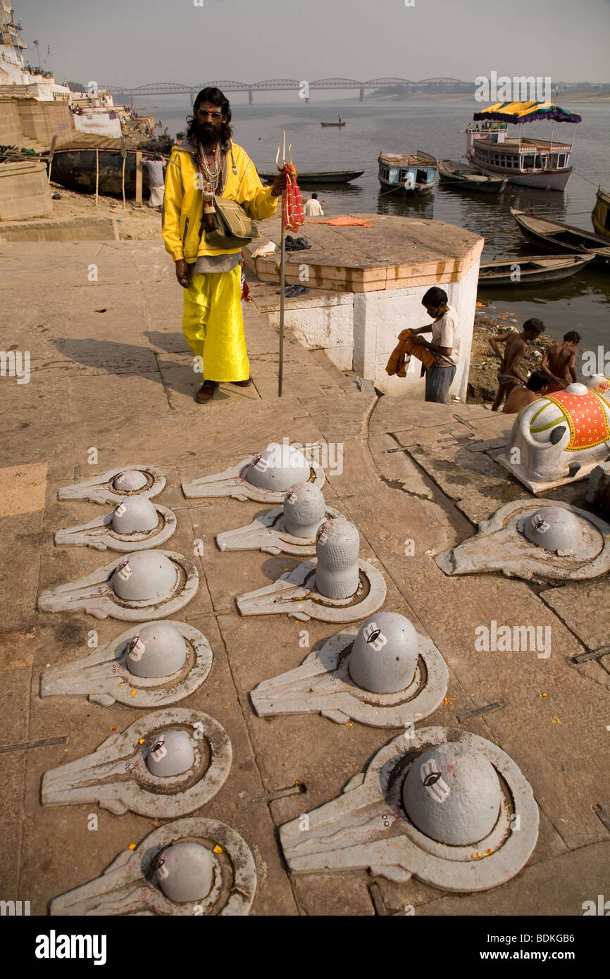 Ein Sadhu in der indischen Stadt Varanasi (Benares). Er steht hinter einer Reihe von Shiva Lingam, eine Art von Phallus-Symbol. Stockfoto