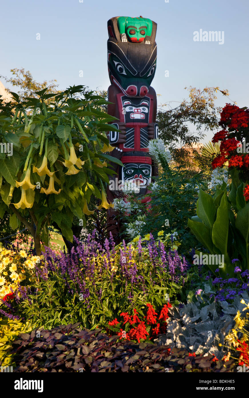 Blumen und ein Totempfahl entlang der Inner Harbour, Victoria, Vancouver Island, British Columbia, Kanada. Stockfoto