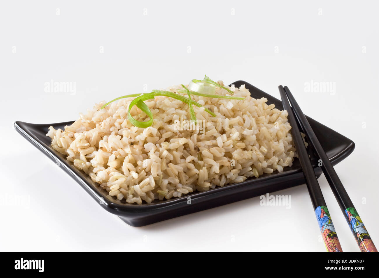 Brauner Reis in schwarze Schale mit Stäbchen Stockfoto