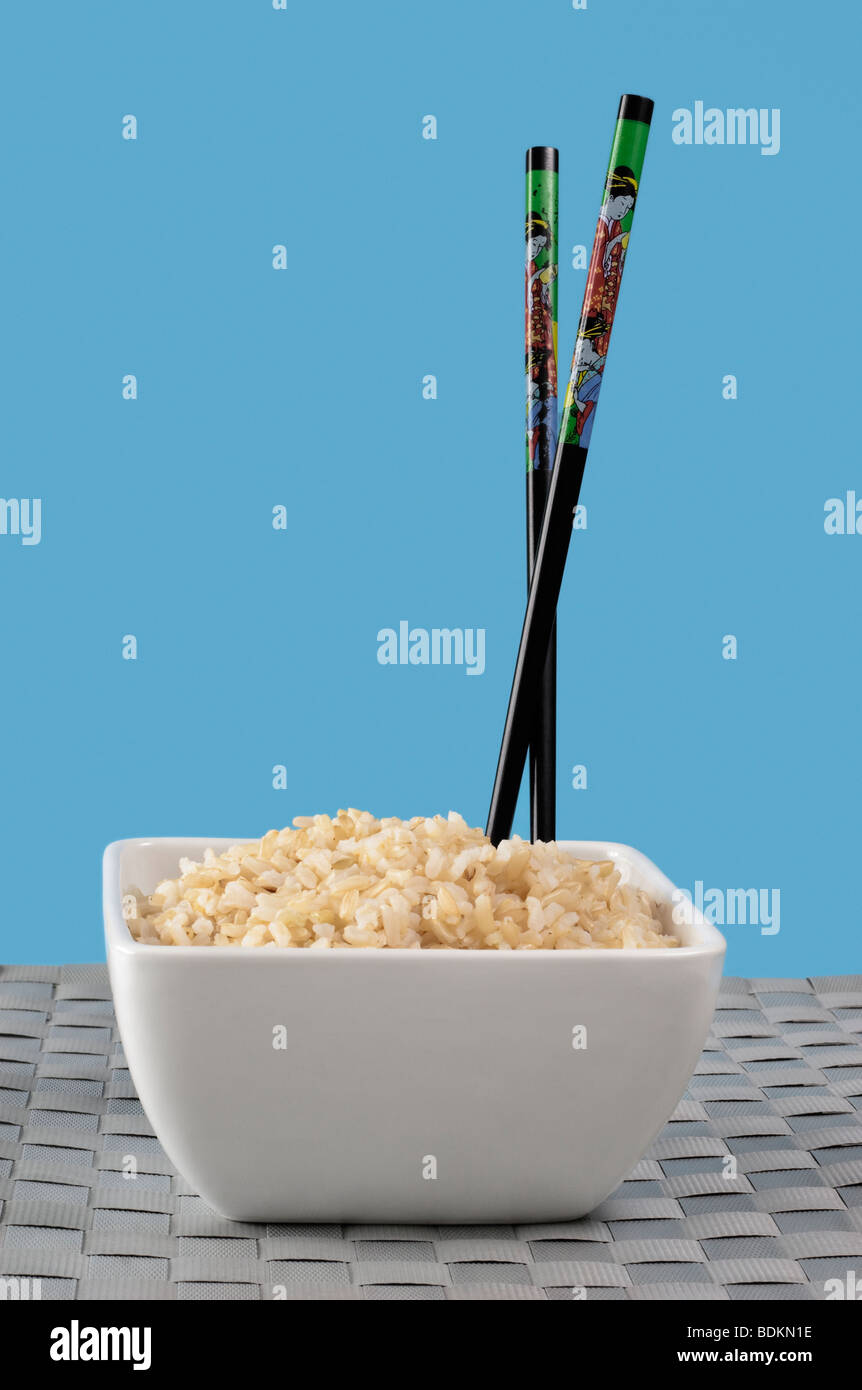 Brauner Reis in weiße Schale mit Stäbchen Stockfoto
