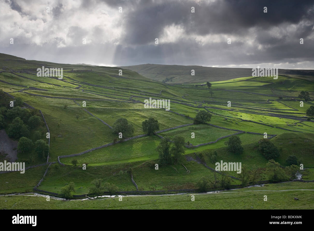 Strahlen des Lichts durch bedrohlich aussehende Gewitterwolken über die Trockenmauer am Shorkley Hill, Malham, Yorkshire Dales Stockfoto
